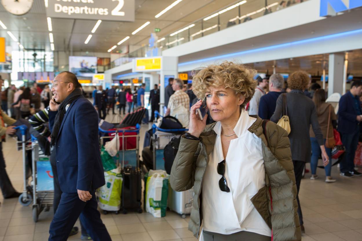 Vrouw belt met mobiel in vertrekhal Schiphol