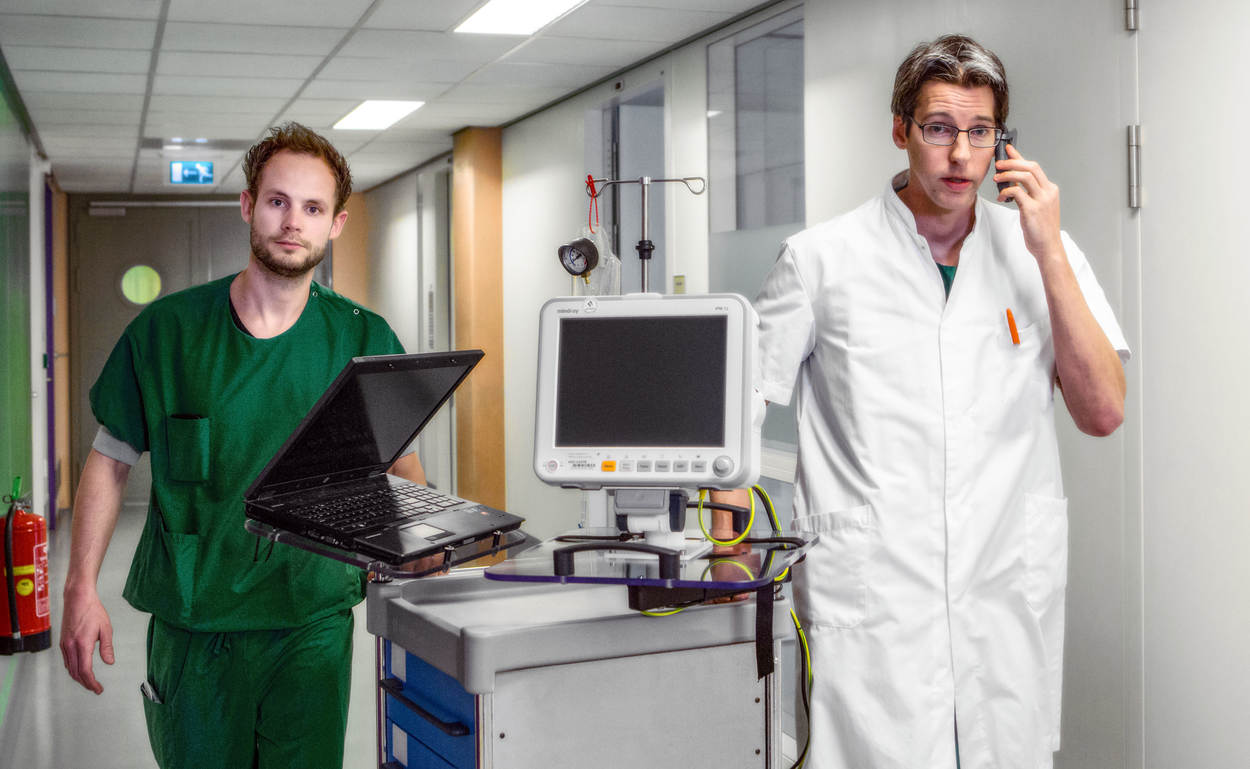 Twee artsen die door een ziekenhuisgang lopen met apparatuur