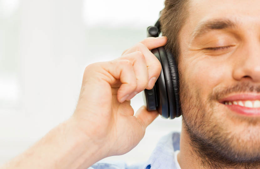 Man met koptelefoon op luisterend naar muziek met ogen dicht