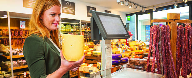 Vrouw in kaaswinkel wil stuk kaas afwegen op weegschaal