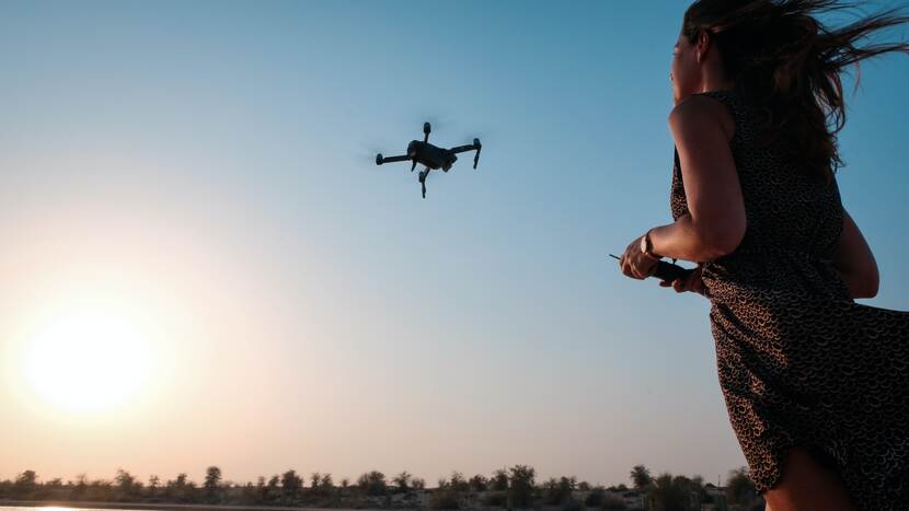 Vrouw die in een open veld een drone in de lucht bestuurt
