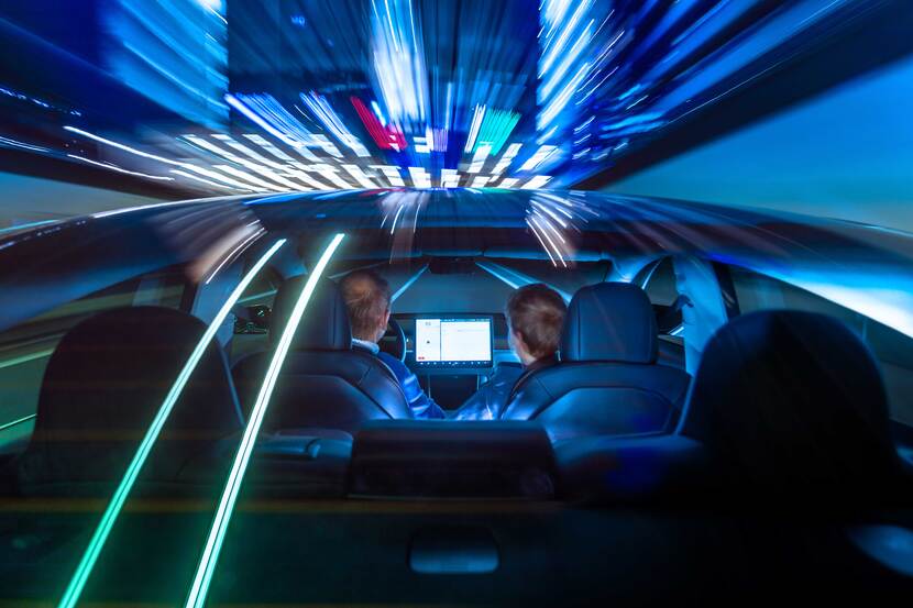 Twee mensen in een auto met lichten die reflecteren op de auto