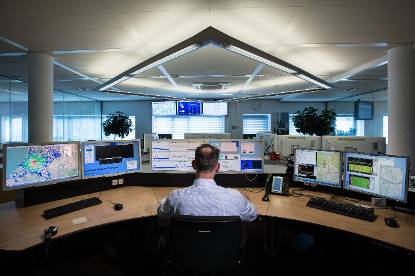 De radio controle kamer van agentschap telecom met een man die achter computerschermen werkt