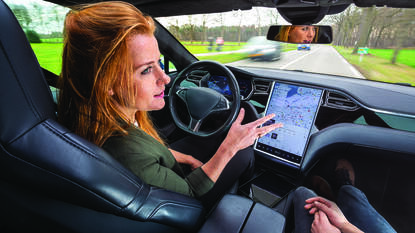 Vrouw in Tesla rijdend zonder handen op het stuur
